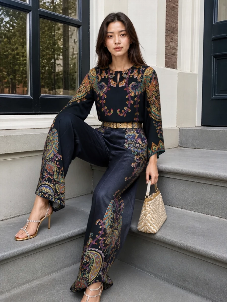 An inky Etro paisley co-ord turns the wide-leg pant into an almost liquid column, with the poncho blouse echoing the motif and moving in sync at every step. A sculptural antique-gold belt and crystal-traced gold sandals add just enough sparkle, while the woven ivory top-handle bag lightens the palette for terrace cocktails or gallery evenings by the sea. The result is romantic, bohemian and decisively polished, all built around that midnight navy ground.