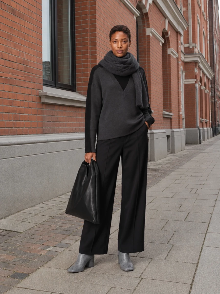 Mm6’s graphic V-panel knit sits over a high-rise black wide leg, keeping the silhouette long and relaxed but still sharply defined. Charcoal ombré ankle boots and the sculptural black Japanese tote continue the grey-to-black story, leaning into quiet, street-leaning minimalism. The compact charcoal scarf finishes it with a precise Margiela signature and a little extra winter depth at the neck.