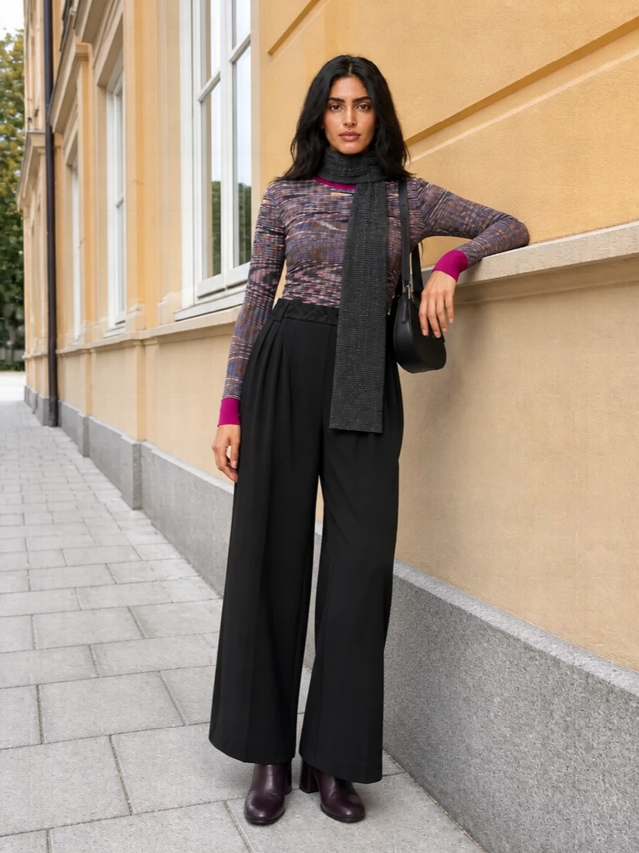 A hypnotic Missoni knit is grounded with fluid black wide-leg trousers for a clean, elongated line that still feels softly bohemian. Plum leather ankle boots pick up the knit’s smoky tones, while a sculpted black shoulder bag and monochrome scarf keep the finish polished and quietly graphic. The result is a refined fall and winter ensemble that moves easily from gallery afternoons to intimate dinners.