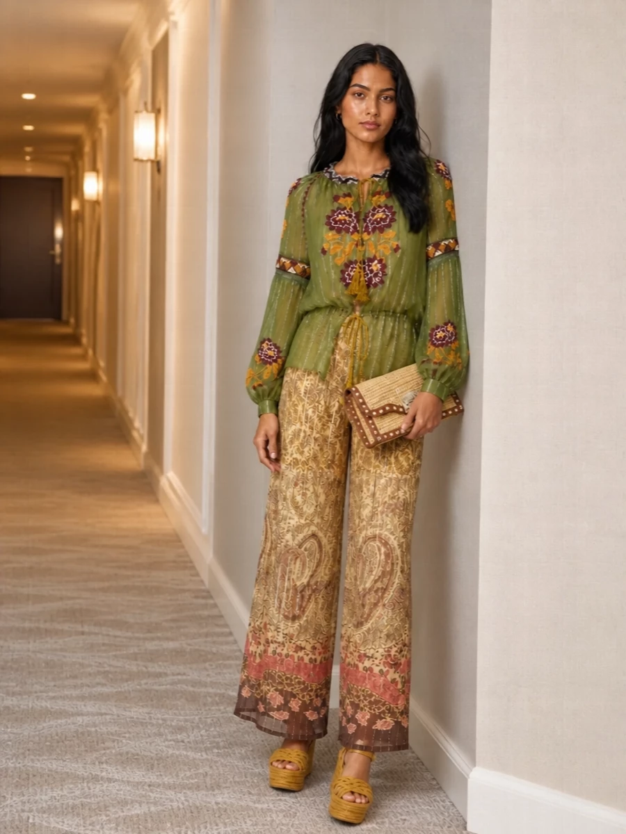 A sheer, embroidered peasant blouse meets equally weightless paisley wide-legs for a romantic, boho column of color that feels made for warm evenings. Mustard and earthy florals speak to each other without feeling matchy, while the raffia wedge and clutch quietly ground the set in sunlit neutrals. The result is relaxed in spirit yet polished enough for terrace dinners and garden parties.