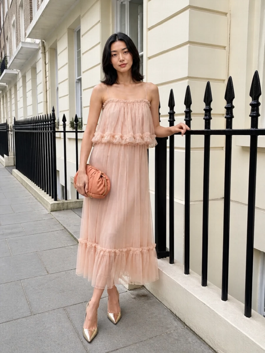 I’m anchoring this with the dress path, because the blush slip’s layered movement and soft nude tone speak directly to the romantic, champagne Louboutin pump in a way separates would complicate. The result is a whisper-light Chloé evening story in blush and champagne, where the fluid slip and gleaming stiletto feel almost bridal yet still perfect for summer cocktails or destination weddings. A peach-nude ruched clutch finishes the palette tonally, keeping the whole ensemble soft, romantic and unmistakably quiet luxury.