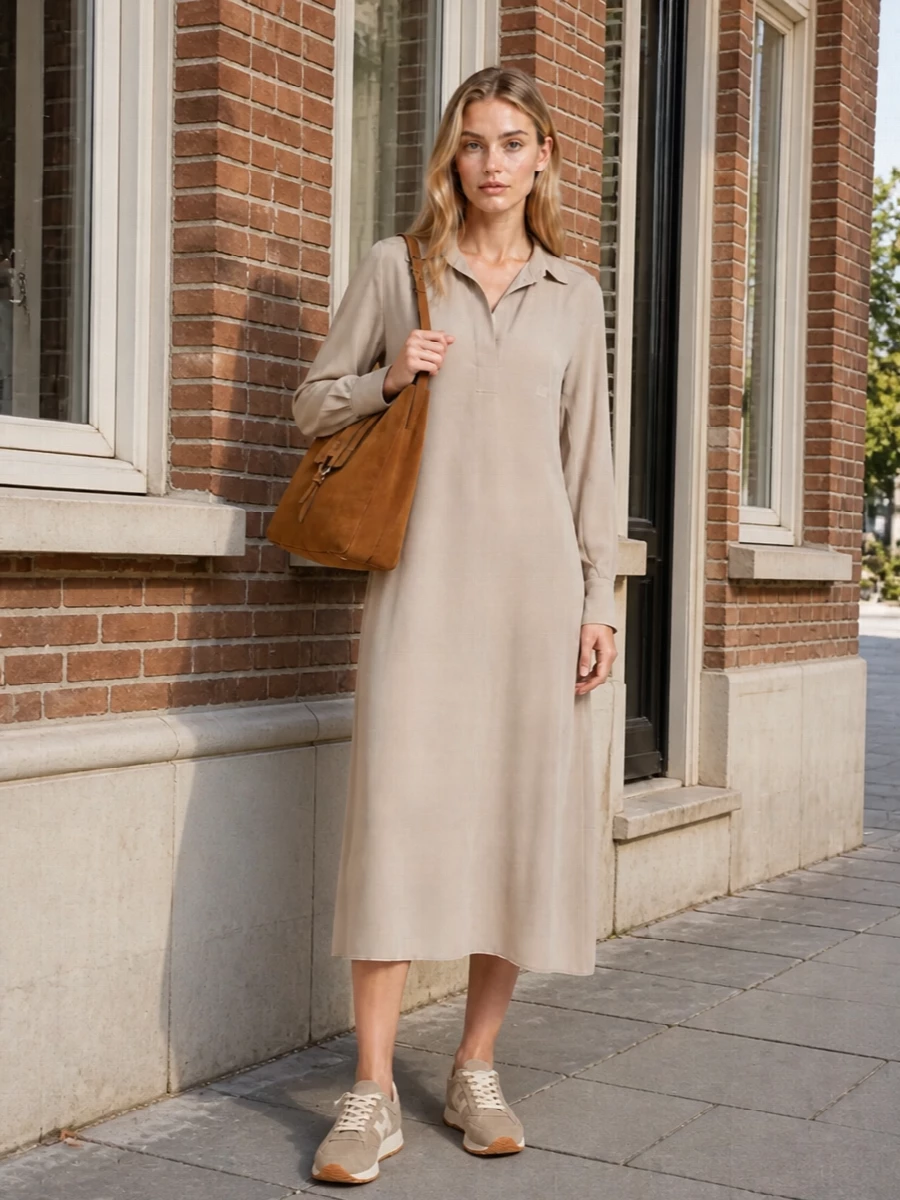 A fluid beige shirt dress and taupe suede sneakers frame the caramel suede tote in a quietly tonal way, all in soft, warm neutrals. The result is relaxed but considered, ideal for city days when you want comfort to read as intentional. Choosing the dress over separates keeps the silhouette long and simple, which lets the textures and subtle color shifts do the work.