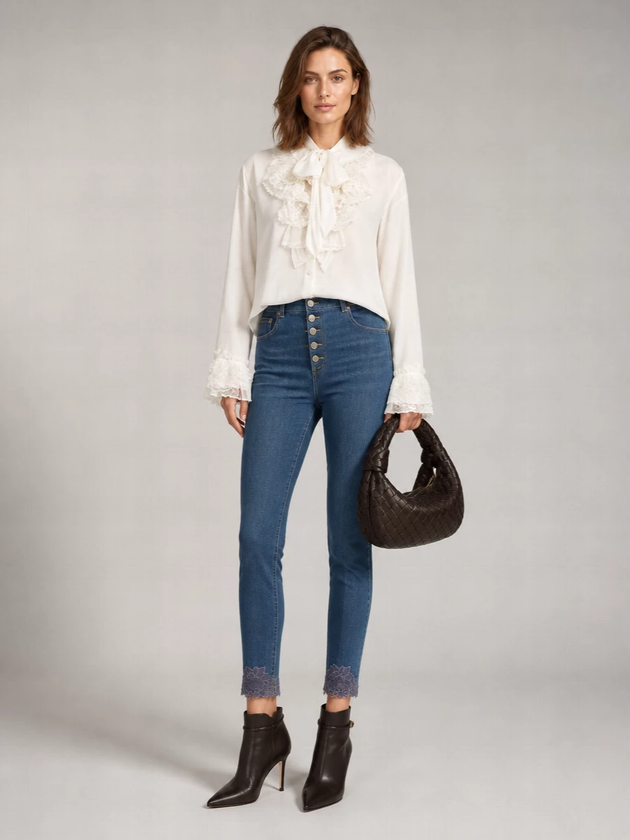 Lace-trim denim meets an ivory ruffled blouse for a romantic, waist-focused silhouette that feels refined yet relaxed. Deep espresso heels and a chocolate intrecciato shoulder bag ground the softness with quiet structure and rich texture. The result is an intimate, evening-ready pairing that whispers luxury in muted tones.