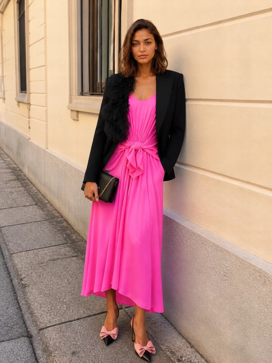 Neon pink drape and sculpted knotting stay in focus, framed by a sharp hit of black and gold for a clean cocktail statement. The Mach & Mach slingbacks echo the dress’s playful movement in a way that still feels polished, while the compact Prada bag keeps the line sleek and modern. It is a bold, nightlife-ready combination that reads luxury rather than novelty, with a wink of Y2K in the details.
