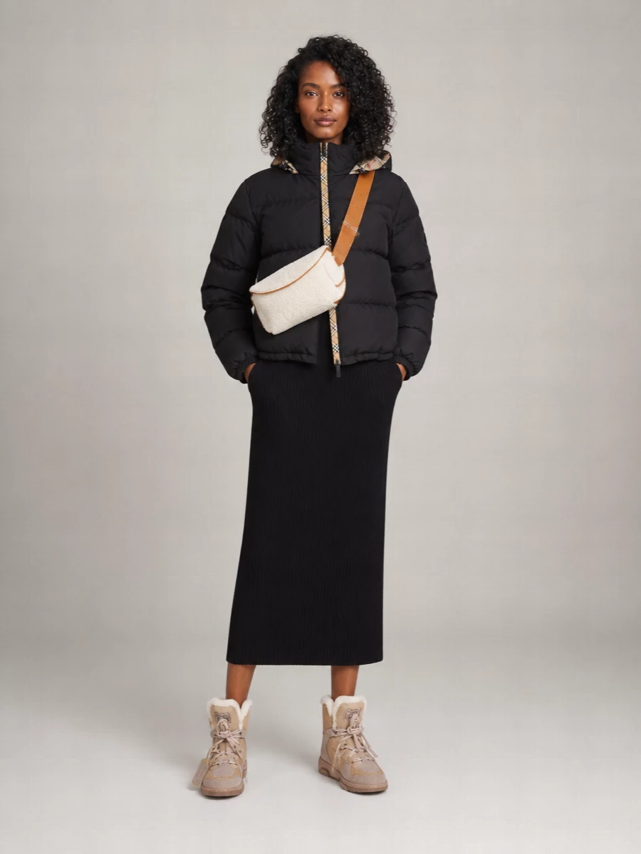 I’m going dress route here, using a straight black ribbed turtleneck dress as a clean column under the cropped Burberry puffer so the jacket stays the hero. Off-White’s sand shearling sneaker boots and the cream shearling McQueen belt bag pull out the warm tones of the Burberry check and push the whole thing into cocooned, high-end streetwear that still feels polished enough for the city. It is a tight, graphic palette with all the interest in texture and proportion rather than print stacking or extra tailoring layers.