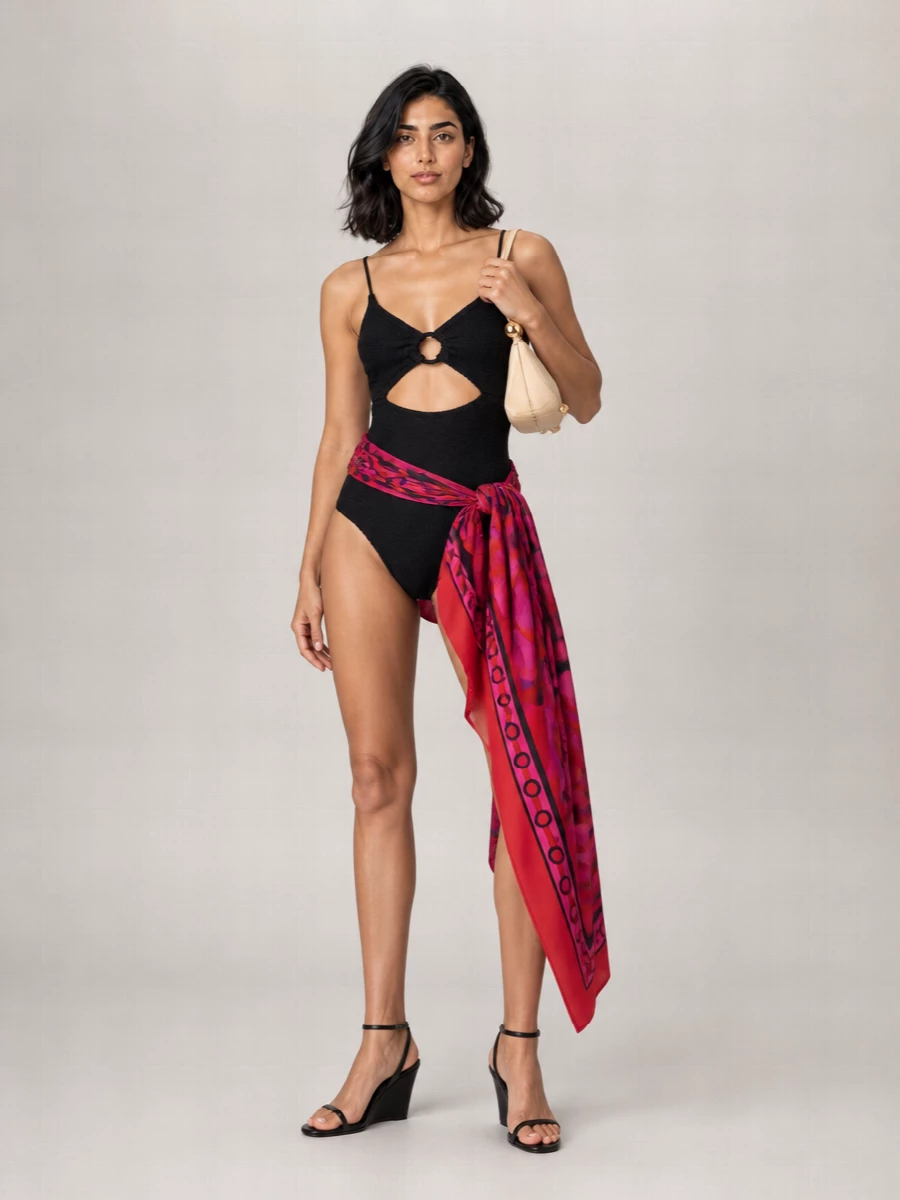Hunza G’s black cut-out one-piece stays firmly in focus, framed with Courrèges’ sharp black wedge sandals for a clean, leggy line. A cream Jacquemus crescent bag and a saturated Pucci pareo wrap bring just enough color and shape to move the swimsuit from pool to cocktail hour without losing its minimalist edge.