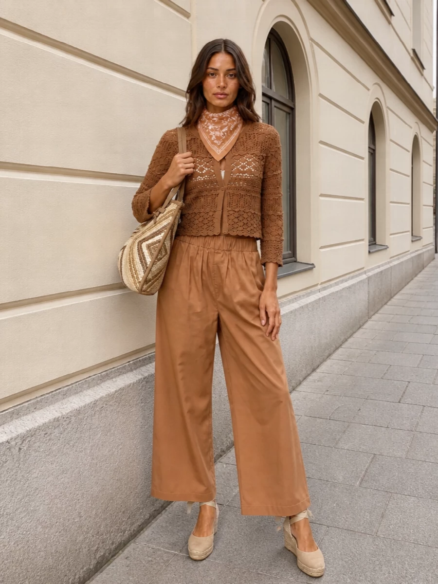 Warm caramel tones and crochet textures create a soft, sunlit take on boho, grounded by fluid wide-leg trousers for ease and flattery. Espadrille wedges lift the silhouette just enough for terrace lunches or garden gatherings, while a woven tote and silk scarf keep the mood relaxed but considered. It is an easy, romantic outfit that feels as good strolling a seaside promenade as it does in the city heat.