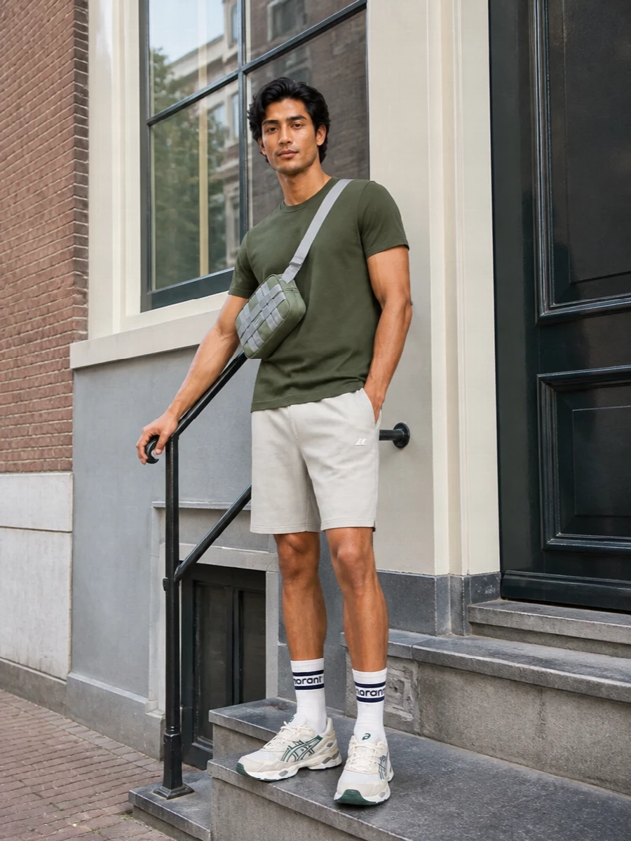 Olive and stone keep this combo clean and grounded, with the tee and technical shorts reading relaxed but still precise. The cream-and-forest runners and matching olive crossbody lean into a sport-driven city vibe without feeling fussy. Graphic striped socks are the one small hit of attitude, peeking out just enough to finish the palette.