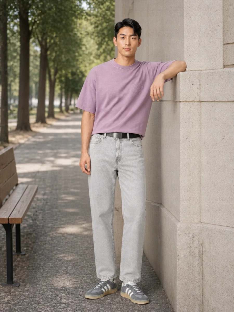 Soft dusty lilac sits on light grey denim for a calm, washed-out streetwear palette that feels easy but considered. Slate suede trainers and a pinstriped tote keep the mood grounded and utilitarian, while the slim black belt gives just enough structure at the waist. The result is a relaxed, spring-ready uniform that feels modern without trying too hard.