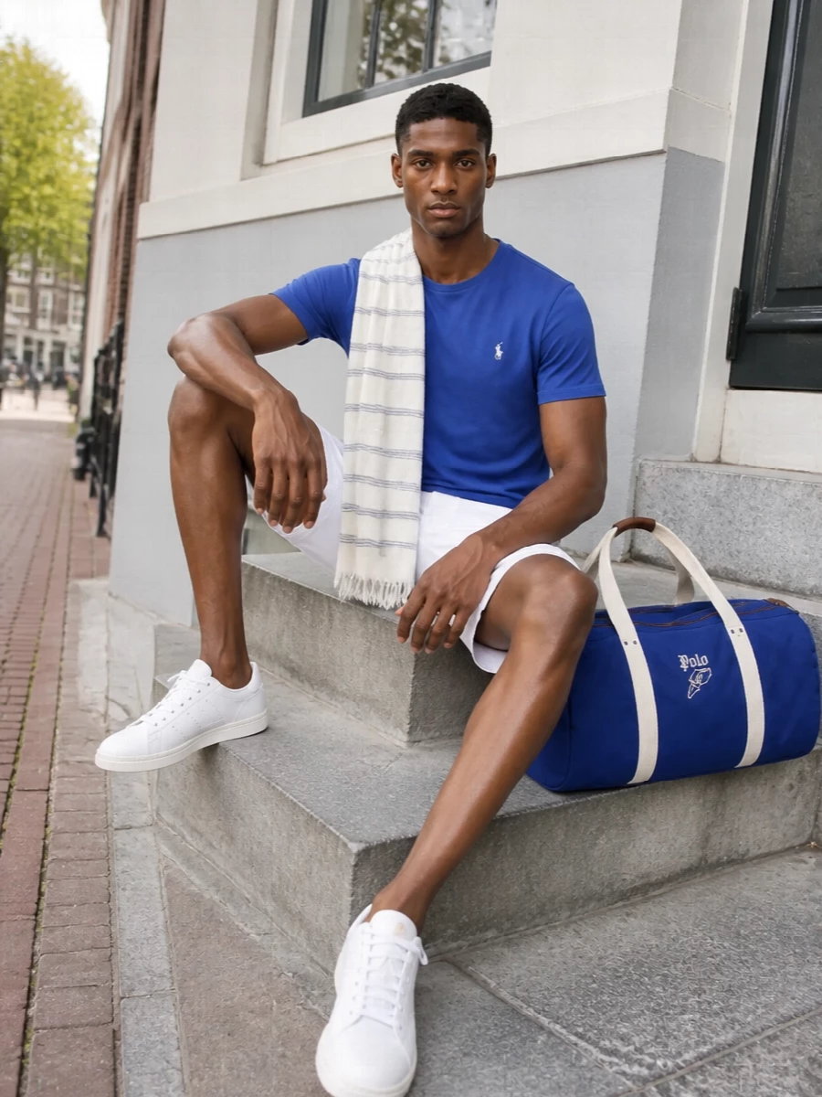 Royal blue and optic white keep this outfit bright and precise, with the chino shorts sharpening the tee into something ready for terraces, ferries or city afternoons. Clean white court sneakers underline the sporty prep, while the matching Polo duffle and a fine striped scarf introduce a subtle coastal cue that still feels polished rather than beachy.