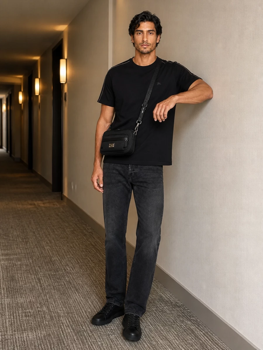 A black Burberry tee and washed-black Haikure denim create a tonal, low-key base that lets the Armani crossbody feel integral rather than extra. Matte black Lanvin sneakers keep the line sharp and urban, giving a clean, minimalist streetwear uniform for colder city days.
