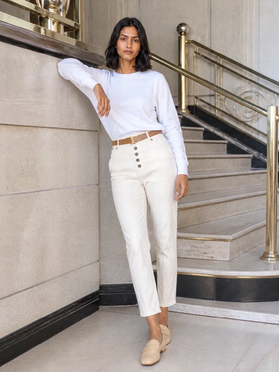 A soft-neutral story built around the off-white tapered trouser, this pairing leans into clean volume on top and precise definition at the waist. The sculptural white knit, butter-toned loafers and taupe top-handle keep everything calm and refined, with the slim camel belt adding just enough structure. It is a quietly composed city outfit that moves easily from desk to dinner without feeling overworked.