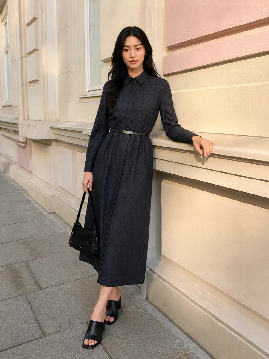 A charcoal Max Mara shirt dress is cinched with a slim leather belt, creating a clean, sculpted waist within its long, fluid line. Black block-heel mules and a compact baguette bag keep the focus on proportion and texture, reading polished enough for dinners yet relaxed enough for late meetings. The palette stays strictly inky and charcoal, so the effect is quiet, assured and very modern.