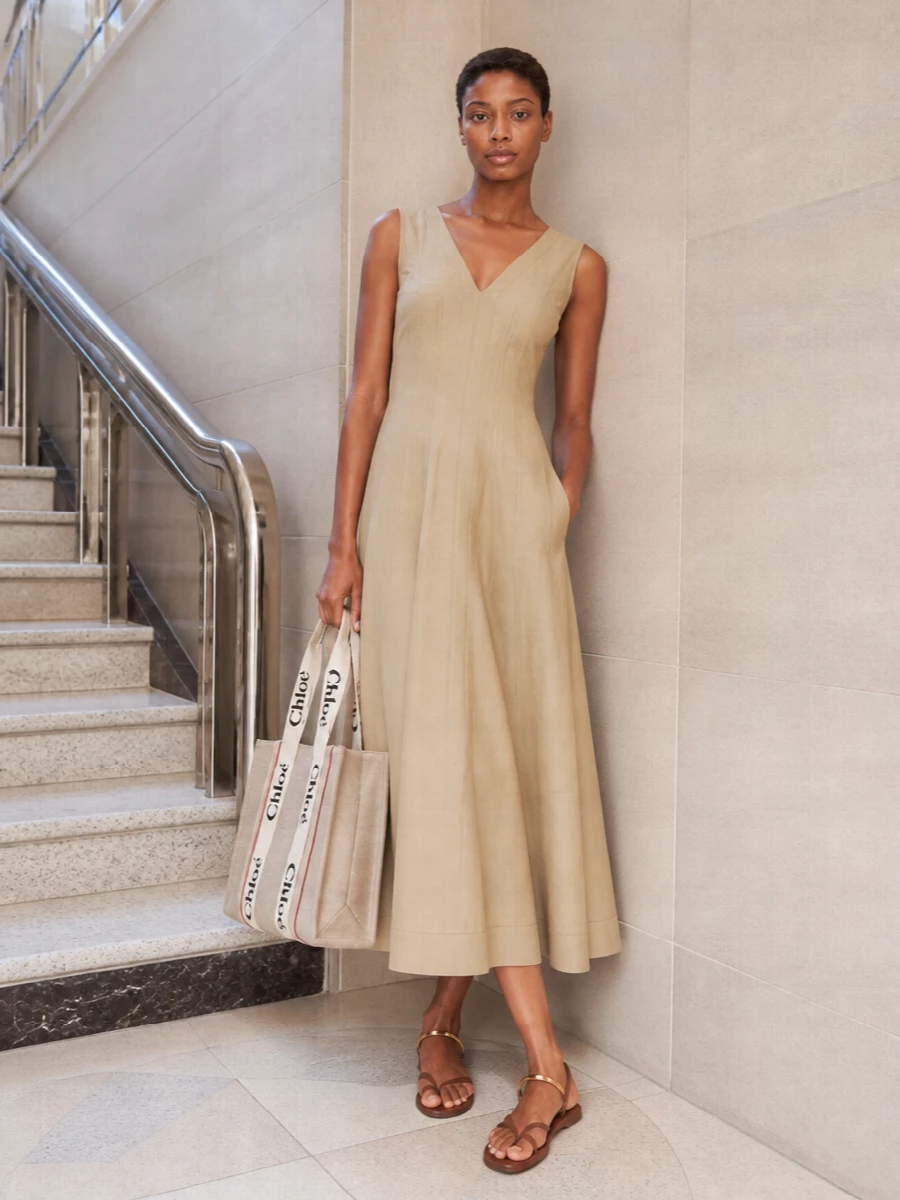 The sand Bottega midi dress is the strongest anchor here, echoing the Chloé tote’s warm palette while adding subtle seaming that reads polished but relaxed for daytime. Leaning into a dress rather than separates keeps the silhouette long and easy, which lets the structured canvas bag feel intentional rather than heavy. Tan flat sandals finish it with a low-to-the-ground, slightly boho ease that still sits firmly in a quiet luxury space.