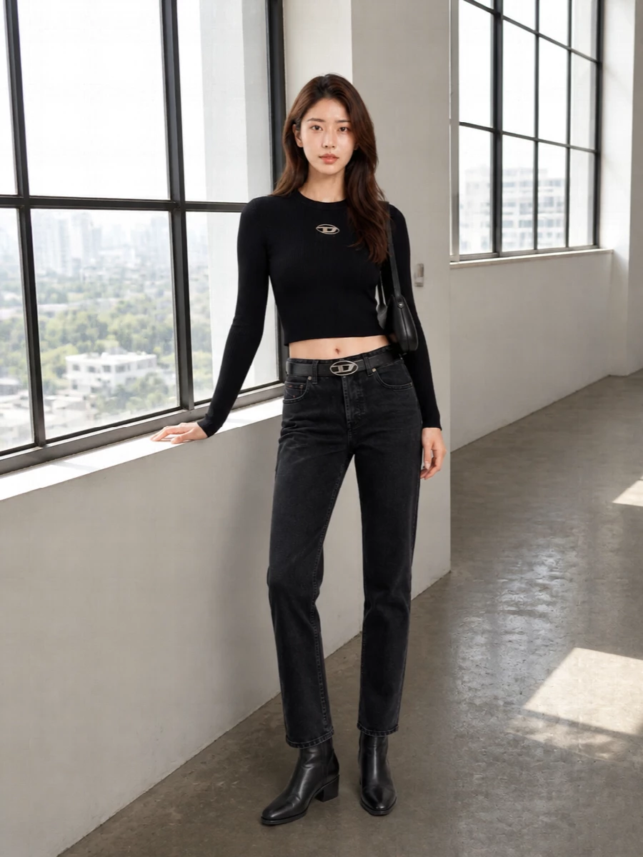 Washed-black denim and a ribbed cropped knit in inky black build a tight, city-right base that feels clean but charged. A low block-heel boot and sculpted black shoulder bag keep everything streamlined and practical, while the silver logo hardware on belt and bag quietly ties the whole palette together for day-to-night streetwear.