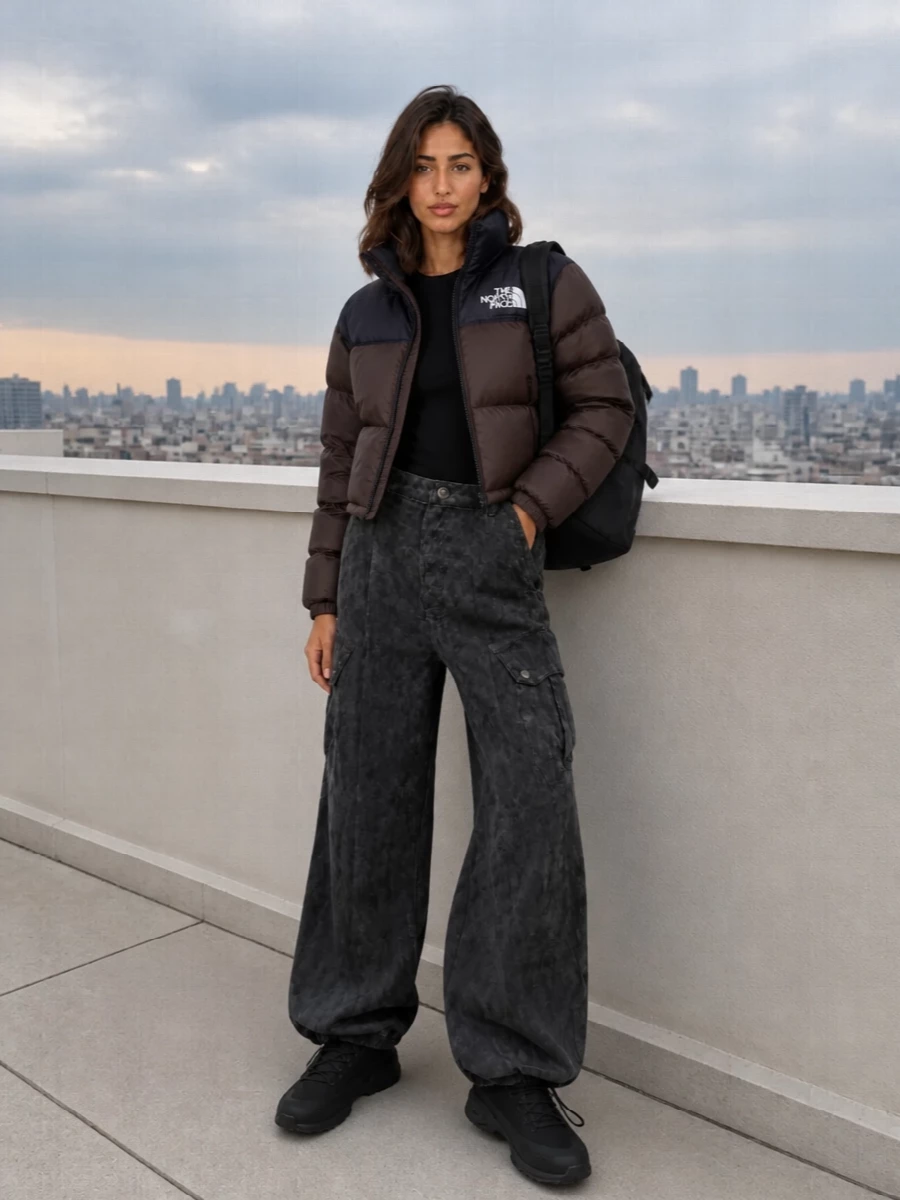 I skipped the dress options to lean into a full street-sport story around the cropped North Face puffer, where cargos and technical sneakers feel more authentic than pairing it with a mini. The slim black base layer and washed charcoal cargo create a strong high-waist, wide-leg line under the boxy jacket, while all-black accessories keep the branding sharp and the palette urban. It is built for cold city days when you want true outdoor function that still reads considered and directional.
