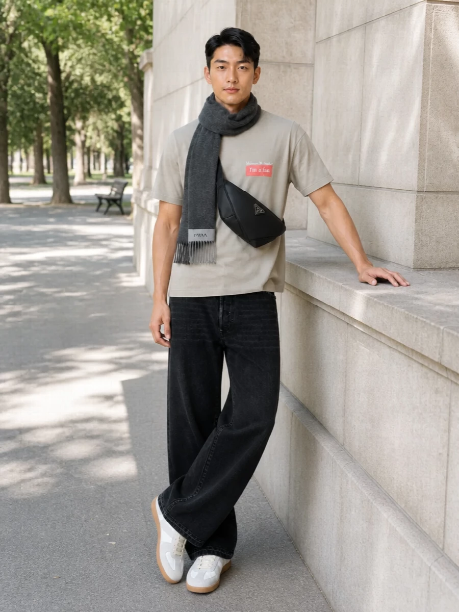 Warm stone and coral stay in focus against the washed black wide-leg denim, giving the tee’s wry print a sharper, more graphic stage. Off-white gum-sole sneakers and a sleek black crossbody keep everything relaxed but precise, a clean city uniform with just enough volume in the leg to feel considered. The charcoal scarf echoes the darker tones up top, so the color story reads tight and intentional from head to toe.