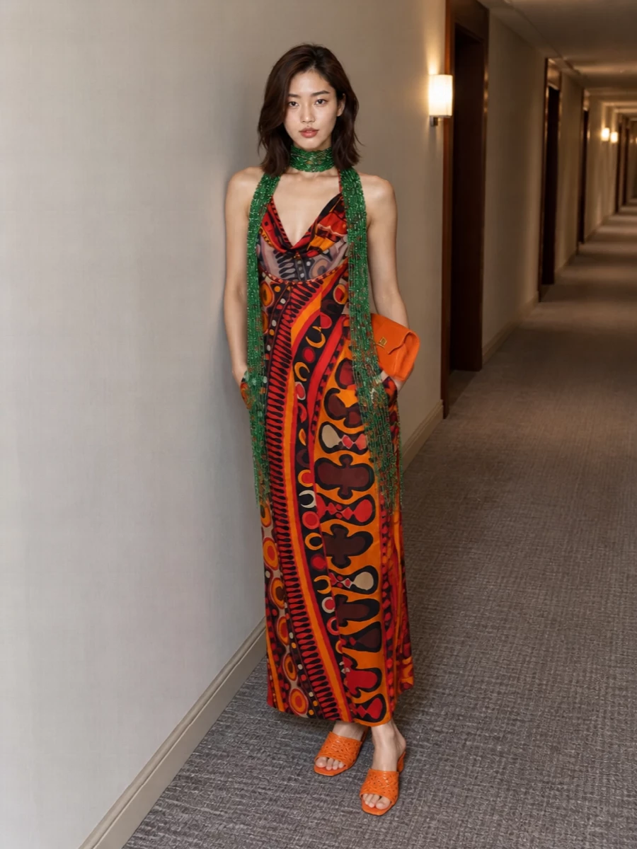A molten Pucci halter maxi stays front and center, framed by sunset-bright orange mules and a sculpted burnt-orange clutch that pick up its fiery tones. The column silhouette remains long and lean, while the metallic textures and that sliver of emerald scarf keep it feeling unapologetically night-out and modern Y2K-glam. Every element is bold, but the clean shapes and tight warm palette keep it cohesive rather than chaotic.