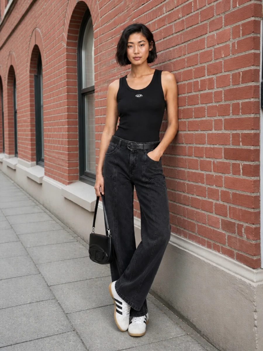 Washed-black wide legs meet a tight ribbed tank for a clean, grunge-leaning street outfit that feels lived-in but intentional. Retro terrace sneakers keep it grounded and low-profile, while a compact black shoulder bag and slim belt pull everything into a sharp, city-ready line. The result is an easy monochrome mix of utility and minimalism that works from daytime errands to late casual hangs.
