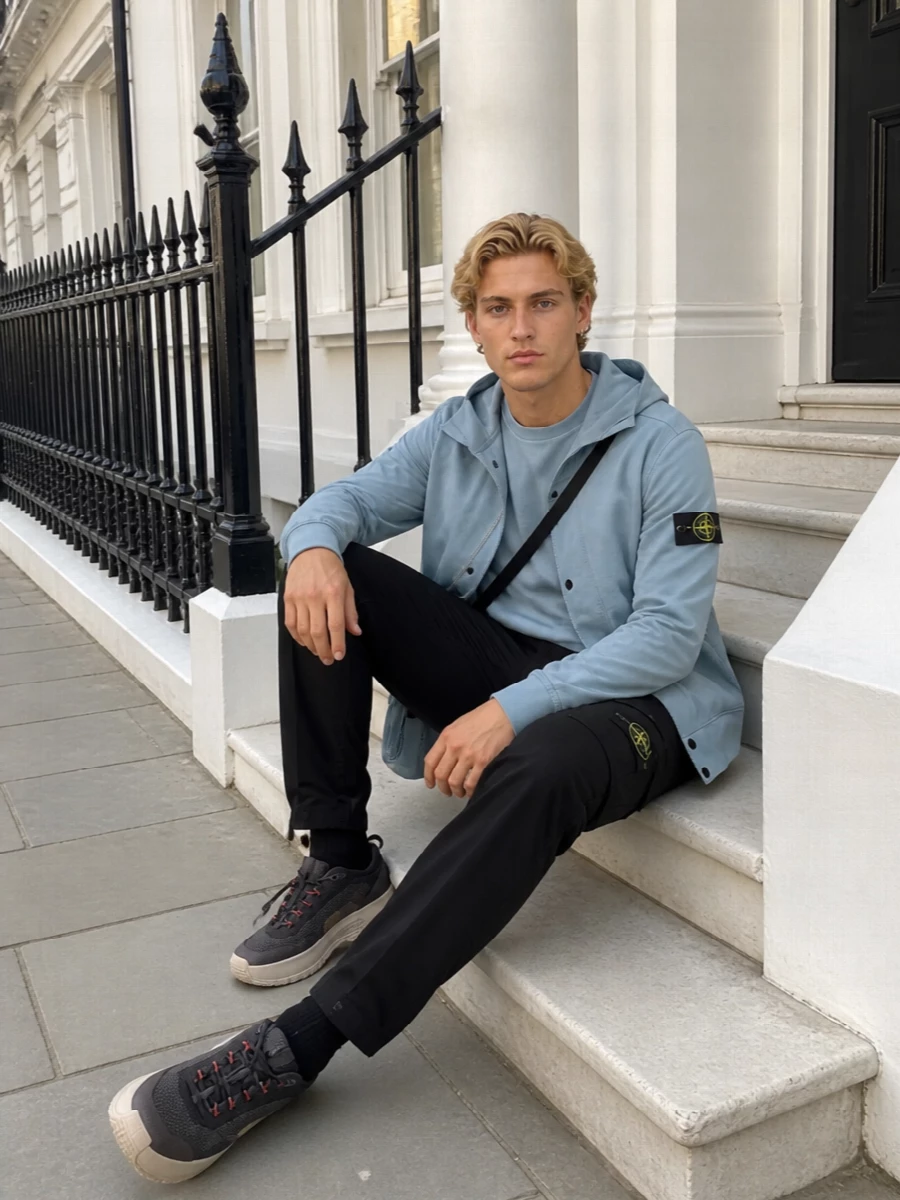 Dusty and powder blues stack neatly against deep black cargos for a calm, technical streetwear uniform. The trail-inspired sneakers and tonal crossbody keep it agile, city-ready and quietly graphic. Every piece speaks the same language of clean utility, just with different textures of blue doing the talking.