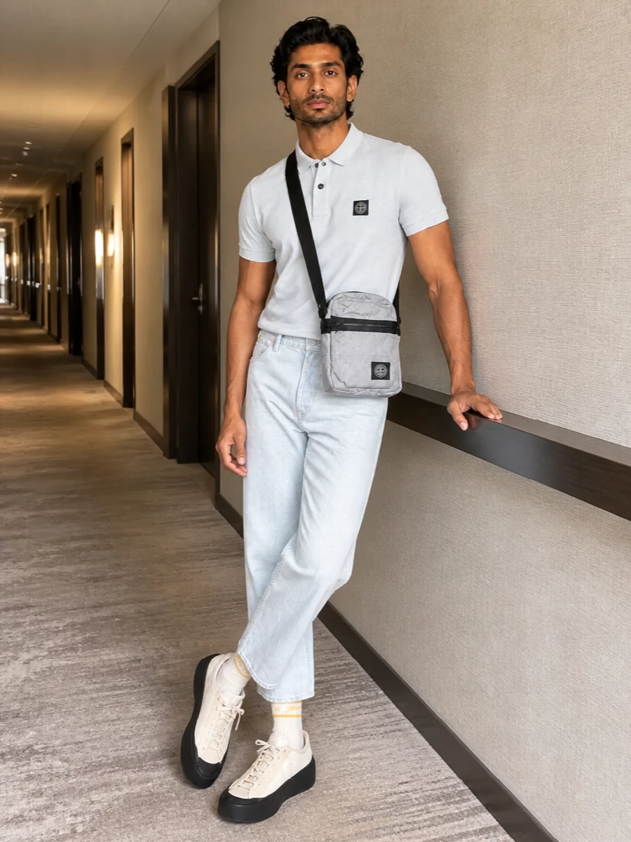 A pale Stone Island polo meets ice-grey denim for a sharp, clean take on street-sport dressing. Neutral technical sneakers and a compact crossbody keep everything light and functional, with striped socks adding a quiet hit of energy. The result is relaxed but precise, easy from city days to low-key evenings.