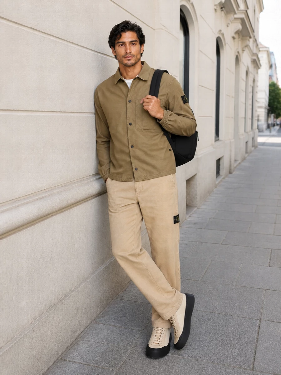 Khaki on sand keeps this Stone Island mix tight and calm, with the straight-leg trouser giving a clean vertical line under the boxy overshirt. Soft technical neutrals and a pale sneaker keep it light, while the black backpack adds just enough contrast and function for city days. The result is relaxed utility that feels considered rather than tactical.