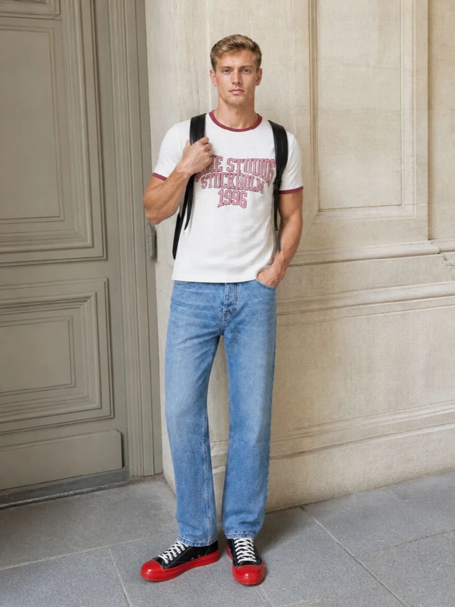 Acne’s varsity ringer tee sits on classic Ami mid‑blue denim for a clean, collegiate base that still feels relaxed and modern. Graphic black and red CDG canvas sneakers pick up the tee’s lettering without overpowering it, while a structured black backpack keeps the whole mix sharp enough for city days or campus runs. The result is easygoing preppy streetwear with just enough intention in the lines and colors to feel considered, not thrown together.