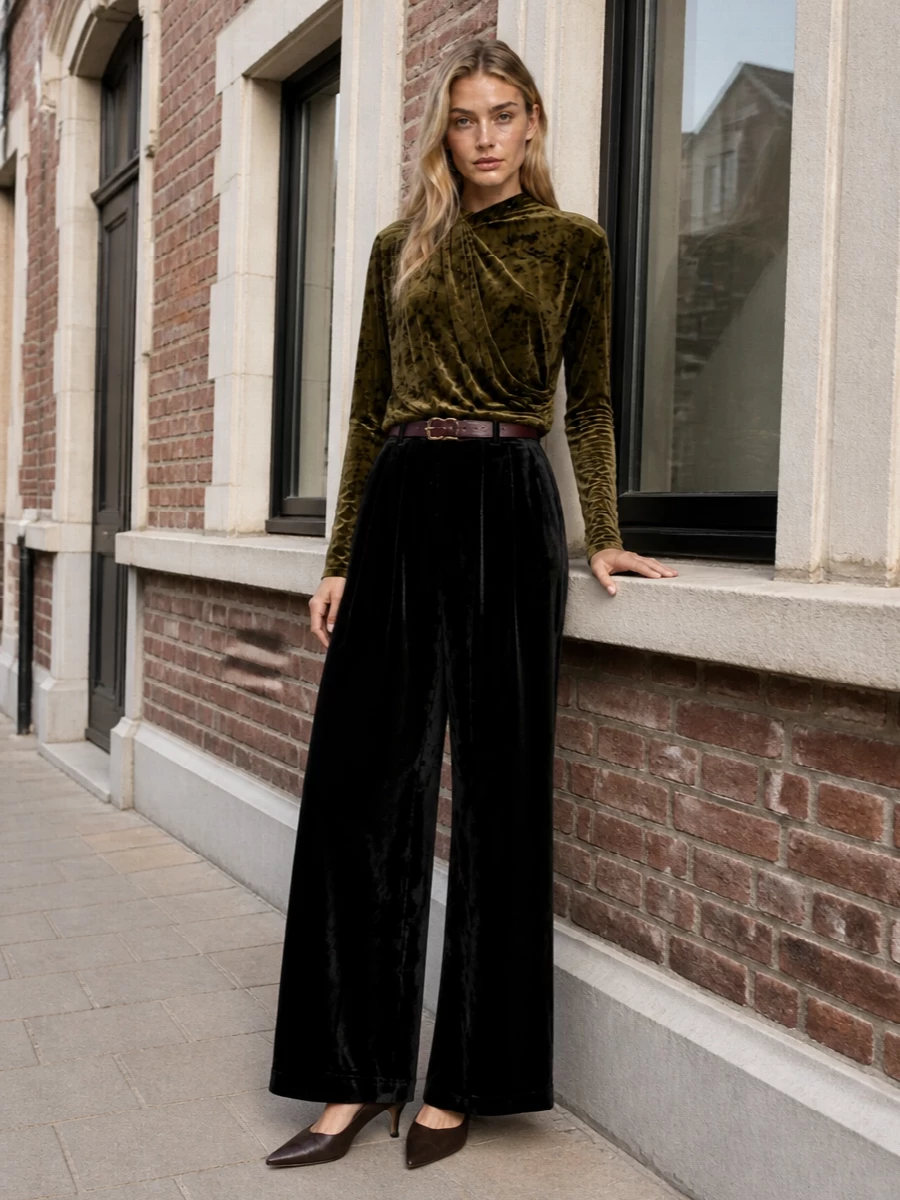 Crushed olive velvet plays against inky black tailoring for a cocktail ensemble that feels plush yet composed. The long sleeve and high neck balance the fluid wide-leg, while chocolate and burgundy accessories keep the mood warm and restrained. It is a quietly dramatic evening combination that reads polished from gallery night to intimate dinner.