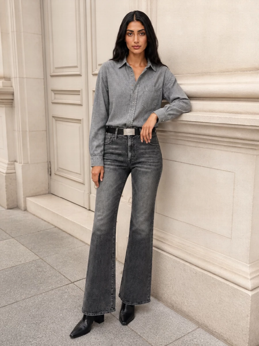 Charcoal flares, a washed grey shirt and sharp black accessories create a monochrome city uniform that feels relaxed but considered. The high-rise denim and slim belt define the waist, while the pointed ankle boots extend the line, keeping the proportions long and lean. It is quiet luxury with a street-aware attitude, ideal from casual office days to late drinks.