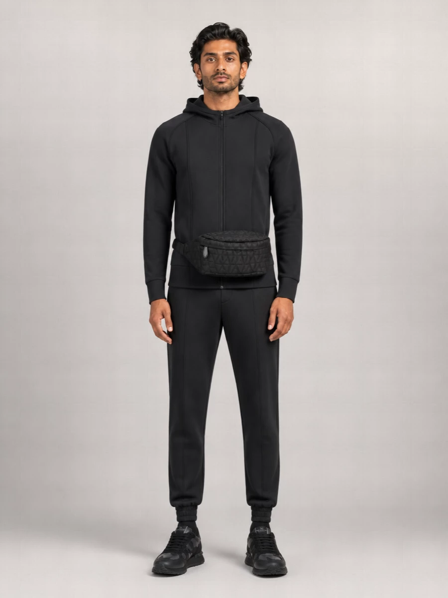 A monochrome Valentino Garavani track-inspired set that treats sport as precision tailoring. The structured zip hoodie and tapered joggers echo the runners’ sleek lines, keeping everything sharp, dark and quietly graphic. Add the belt bag high on the waist to underline the city-ready, technical attitude without diluting the minimalism.
