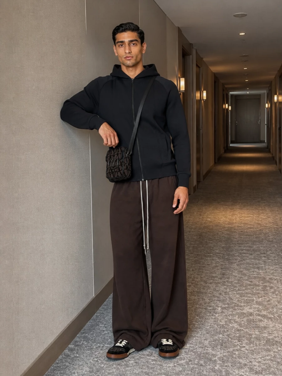 Fendi’s monogram skate sneaker grounds a deep, moody palette, picked up by the charcoal Valentino zip hoodie for a clean, low-key top block. Rick Owens’ ultra-wide chocolate joggers exaggerate the silhouette in a deliberate way that feels modern and directional, while the compact Valentino crossbody ties together the black and brown story with a sharp, graphic note. The result is luxe streetwear that reads intentional rather than loud, perfect for city days that run long.