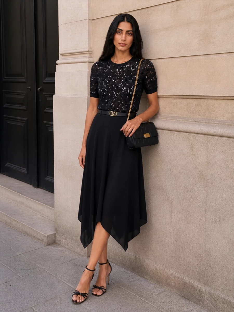 This look builds a dark, romantic column with the sequinned lace tee grounded by a fluid asymmetric black midi, creating movement without overwhelming detail. Nude-and-black stilettos and a quilted black shoulder bag keep the silhouette elongated and polished, while a slim VLogo belt quietly defines the waist for an impeccably modern cocktail ensemble.
