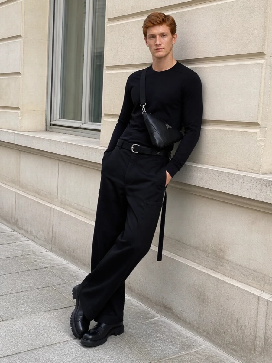 This look builds a stark, columnar silhouette around the high-waisted wide-leg DRKSHDW trousers, anchored by a longline black tee with a single asymmetric tie for quiet disturbance. Off-White’s treaded Chelsea boots add weight and height at the base, while a sleek black Prada crossbody and a wide D-ring belt introduce precise, technical touches that keep the outfit dark, utilitarian and sharply put-together for FW city wear.