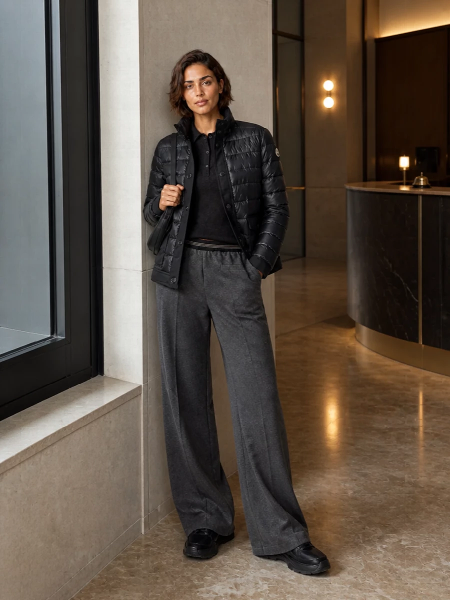 I’m steering away from the dresses here, keeping the story athletic and quietly expensive with a knit, track pant and sneaker combination that belongs under a Moncler puffer. The cropped inky cardigan and long charcoal wide leg create a strong vertical line, while tonal black accessories keep everything calm and city-ready rather than overtly sporty. It reads as considered off-duty, ideal for travel days or low-key meetings where you still want precision in the silhouette.
