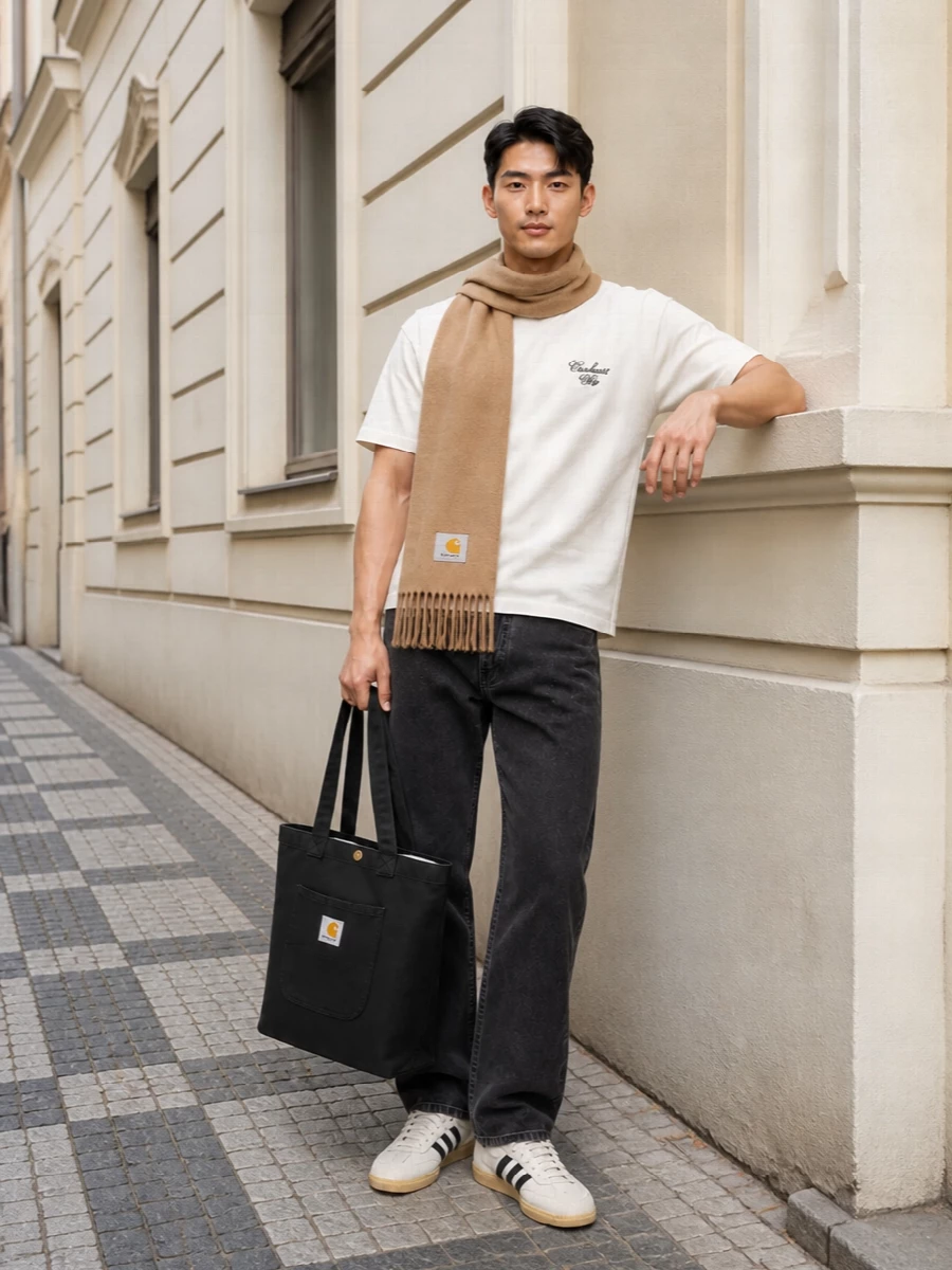 Off-white Carhartt WIP on top, washed black denim below, this is a clean streetwear uniform that leans into workwear without feeling heavy. The cream and black Adidas terrace sneakers echo the palette and keep it skate-adjacent, while the black tote adds just enough structure for a commute or all-day city run.
