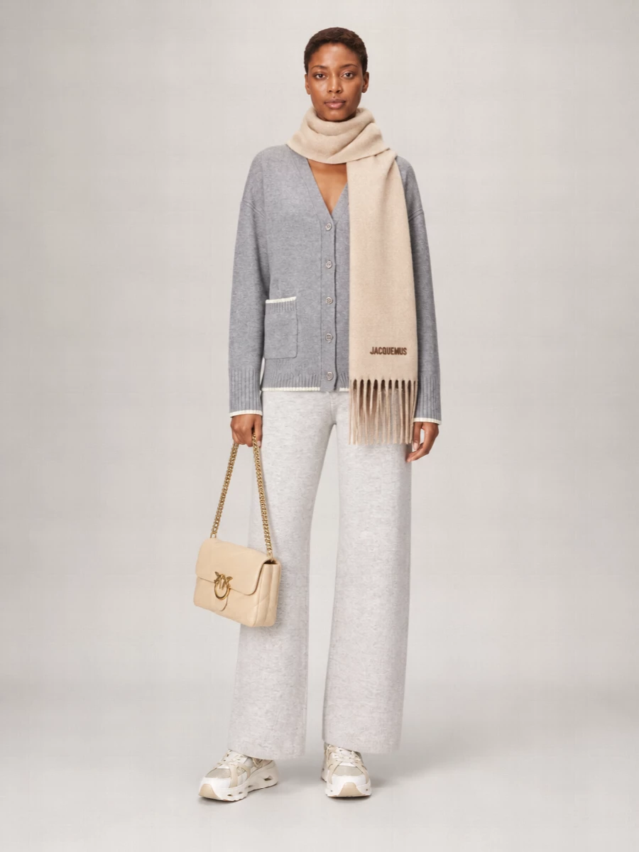 A cocooned knit pairing in layered greys sets the tone, with the wide-leg pant echoing the cardigan’s softness for a quiet, at-home-to-errands foundation. Off white and champagne sneakers and a buttercream quilted bag lift the neutrals just enough, while a brushed beige scarf threads the warm tones through for a soft, complete finish.