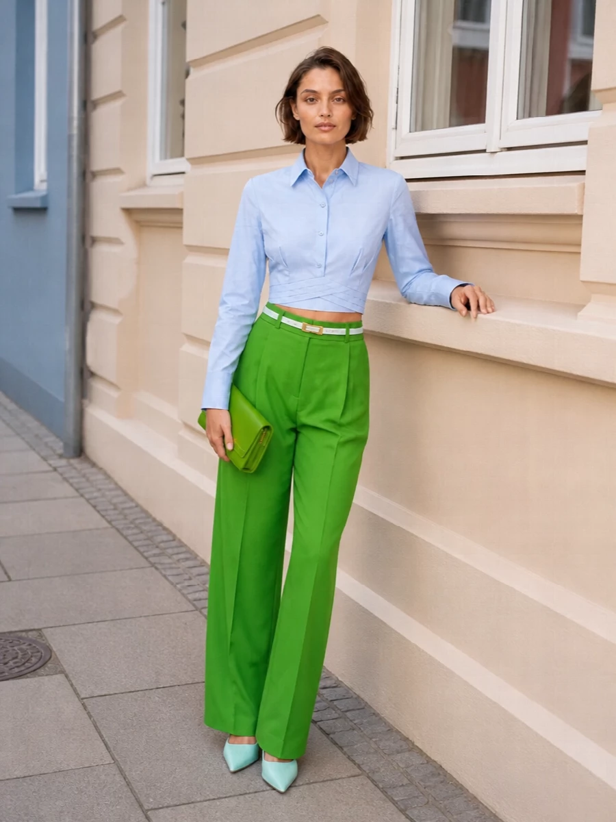 High-waisted green tailoring is cropped with a precise pale blue shirt, then sharpened with mint heels for a fresh, graphic color story that still feels polished. The green clutch and slim white belt tie the proportions together, keeping everything clean and intentional for city evenings or confident daytime meetings.