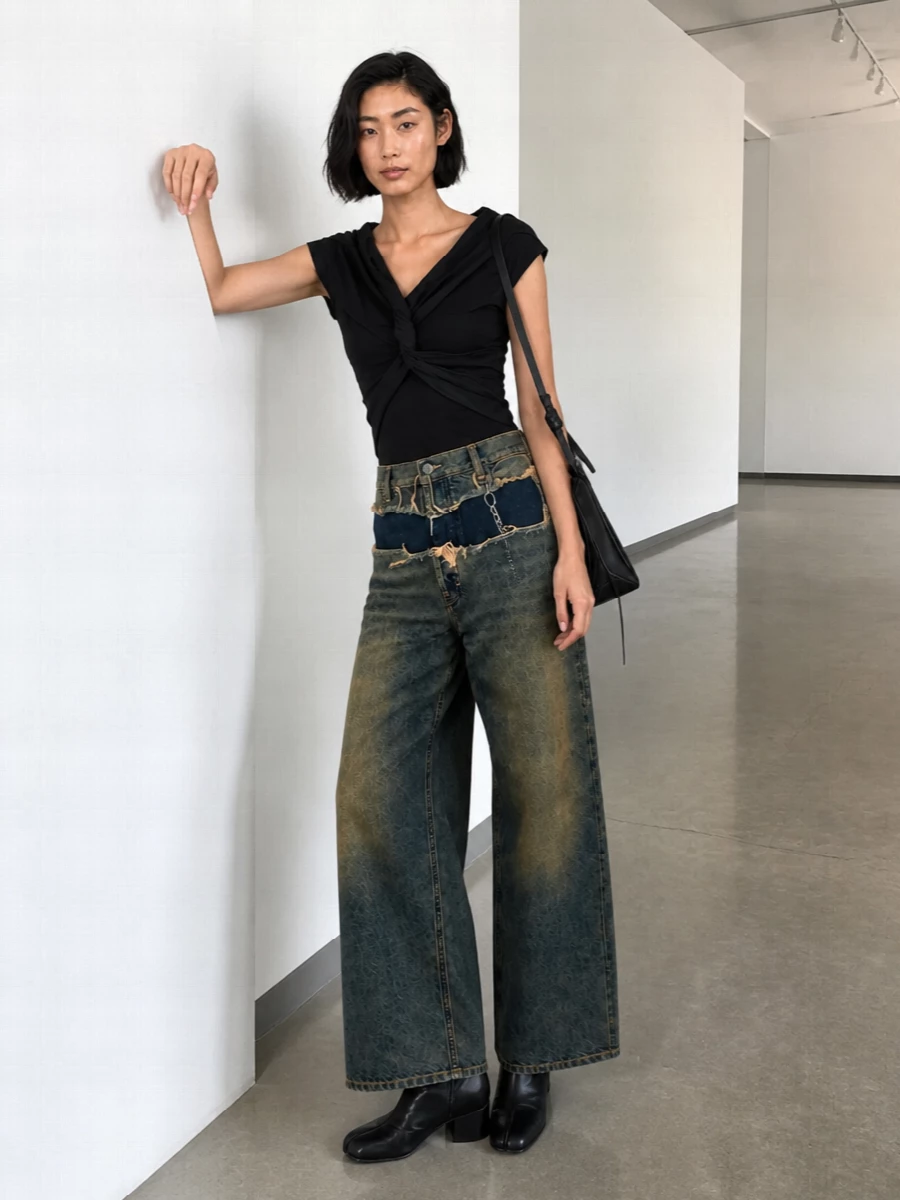 A sharply subversive Margiela uniform built around that deconstructed high-rise denim and a twisted black body that reads like refined second skin. Clean black boots and an angular shoulder bag keep the palette strict and urban, while the chain belt quietly punctuates the exposed waistband for a considered, street-leaning finish.