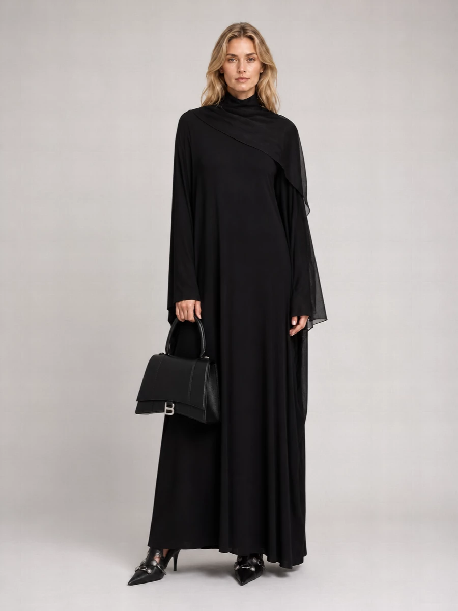 An all-black Balenciaga evening ensemble that reads like modern ceremony, where the liquid column dress does the speaking and everything else simply sharpens the message. Needle-point pumps and a structured top-handle keep the mood austere yet intentional, while a gauzy black wrap adds the faintest suggestion of movement without disturbing the column.