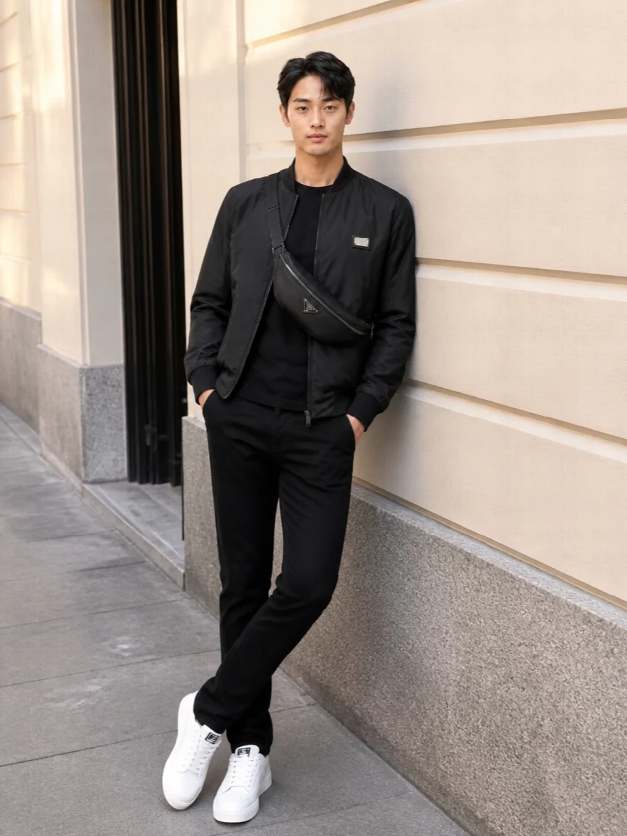 A strict black base, punctuated by a single hit of white at the sneaker, keeps this Dolce&Gabbana bomber story sharp and assured. The Prada crossbody folds in technical polish without disturbing the clean, urban line. It is a quietly branded uniform for days that move from coffee runs to late dinners in the same city stride.