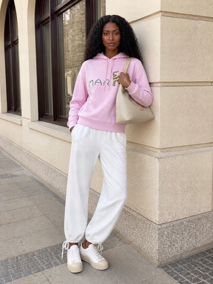 Pastel Marni streetwear goes crisp and graphic with soft white track-inspired trousers and sculptural platform sneakers. The result is an off-duty uniform that feels playful in colour but precise in line. A supple stone hobo tote adds just enough structure to keep the whole ensemble city ready rather than purely sporty.