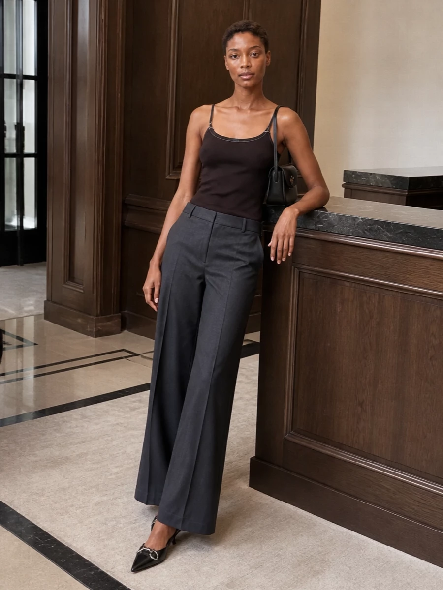 A deep espresso camisole meets charcoal wide-leg tailoring for a clean, elongated line that feels relaxed yet considered. Black slingback kitten heels and a structured black shoulder bag keep the palette disciplined and minimal, letting subtle hardware and texture do the work. The result is quietly sensual evening dressing that moves easily from dinner reservations to late drinks.