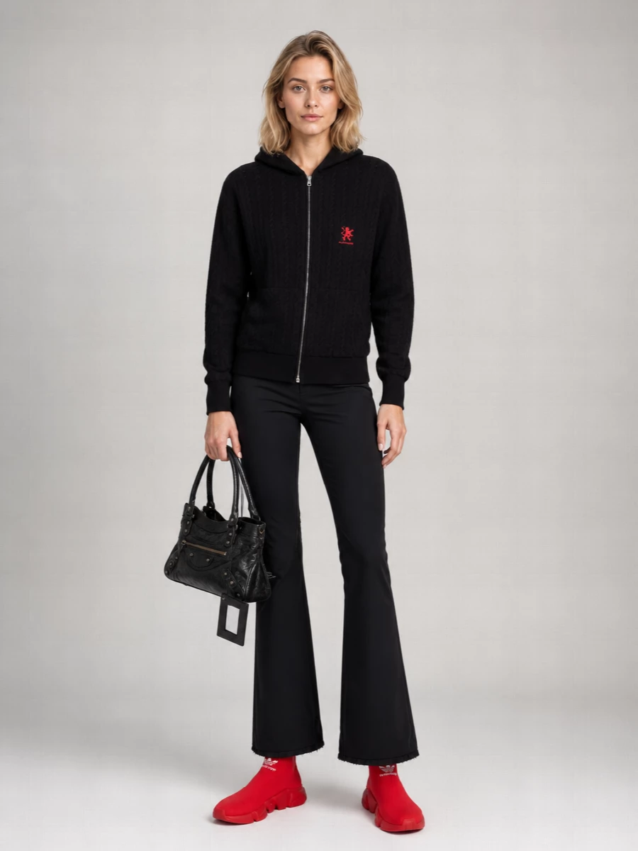 Balenciaga’s cable-knit zip hoodie meets technical flared pants for a street uniform that feels sporty but sharply intentional. The scarlet sock sneakers echo the chest logo so the red reads curated, not random. A worn-in black leather shoulder bag grounds it all with just enough polish to move from errands to evenings out.