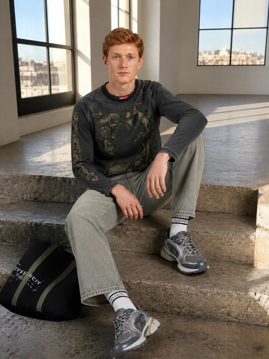Charcoal and washed grey set a dark, graphic base, with the fantasy tee and sun-bleached denim working together instead of fighting for attention. The straight-leg jeans keep the proportions easy and familiar, while the technical runners and logo tote inject a sharper, city-ready energy into the mix. It feels like off-duty streetwear with a subtle medieval twist rather than full costume.