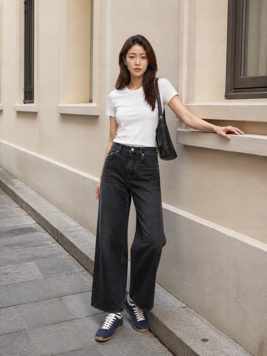 Soft white Kenzo jersey on top with washed black wide-leg denim creates a clean, relaxed streetwear base that feels easy but intentional. Navy low-profile sneakers and a black slouchy shoulder bag keep the palette tight and grounded, while the striped socks add just enough graphic edge without overwhelming the simplicity.
