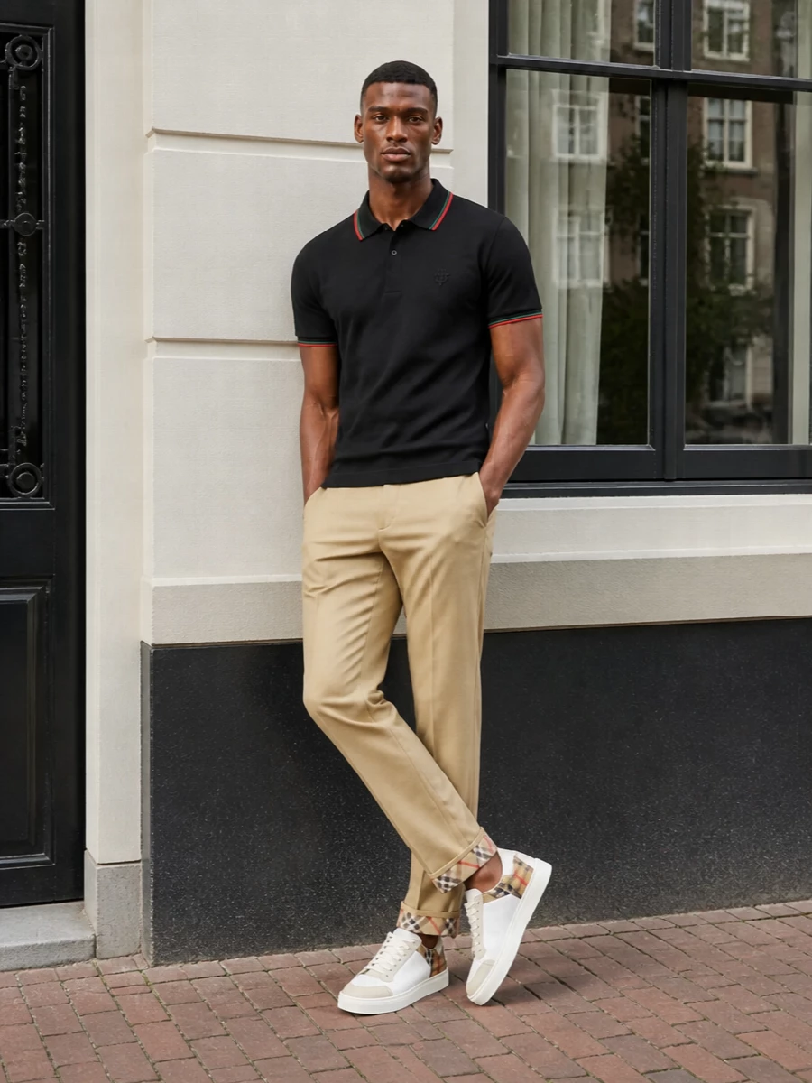 Gucci’s black polo sits clean against Burberry’s beige chino, giving you a smart preppy base that still feels relaxed. White court sneakers keep the palette light and sharp, while the pistachio Bottega crossbody quietly echoes the green at the collar for a considered, modern finish.