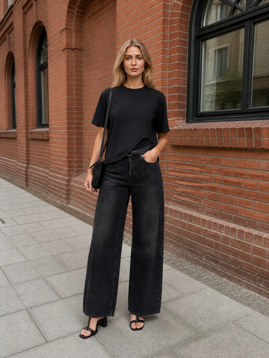 Washed-black wide-leg denim meets an asymmetric tee for a monochrome, street-led base that feels easy but sharply considered. A square-toe mule and slim black leather cross-body add quiet structure, while a narrow belt defines the high rise so the volume reads intentional rather than oversized.