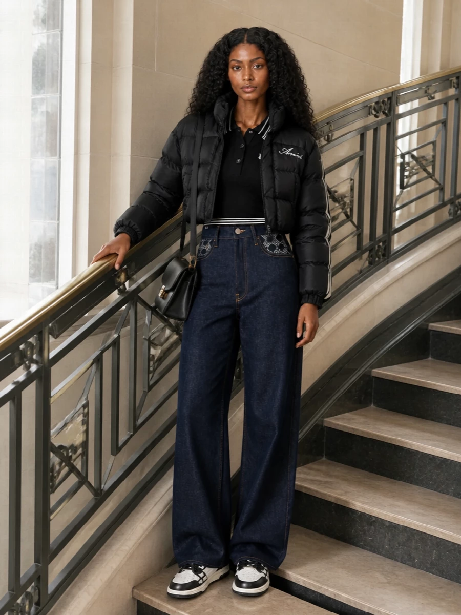 I am building this around the jacket with separates rather than a dress, so you keep that cropped puffer as the clear hero over sharp denim and sneakers. The striped Amiri polo locks in the varsity theme without feeling matchy, while the dark wide-leg jeans and monochrome court sneakers stretch the silhouette into a long, easy line. A structured black shoulder bag from Ami Paris finishes it with a touch of Parisian polish that keeps the whole outfit street, not sloppy.