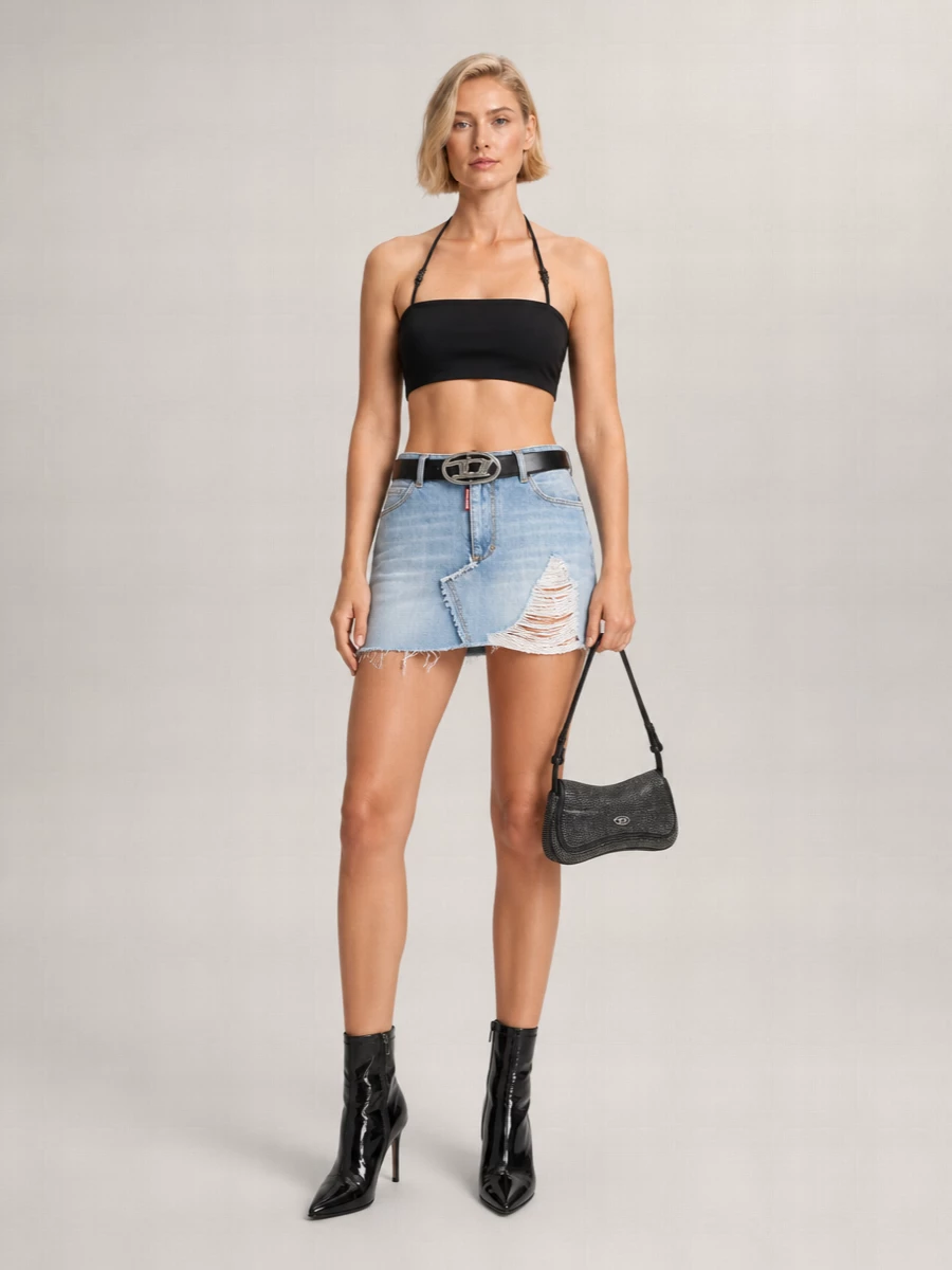 A slashed light-wash mini meets a stark black bandeau for a pure late‑night Y2K mood, all sharp lines and exposed waist. High-shine pointed ankle boots and a rhinestone baguette deepen the dark glam contrast against the destroyed denim. The logo belt pulls it together at the waistband, keeping the silhouette tight and graphic from hip to heel.