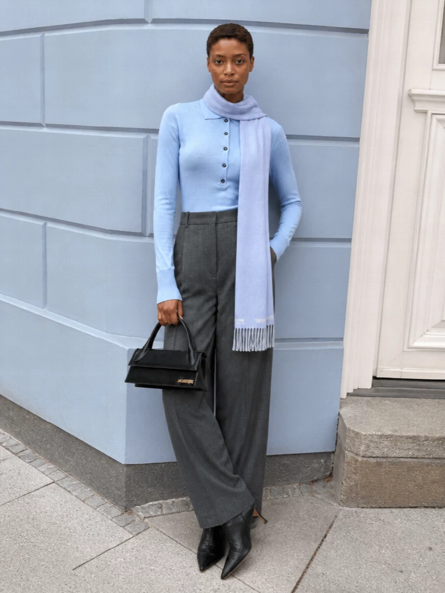 Powder blue and charcoal meet in a clean, elongated silhouette that feels quietly assured rather than showy. The wide tailored trouser balances the bodysuit’s close fit, while sharp black accessories frame the palette with a precise, modern finish. It is polished enough for serious days yet still relaxed in attitude.